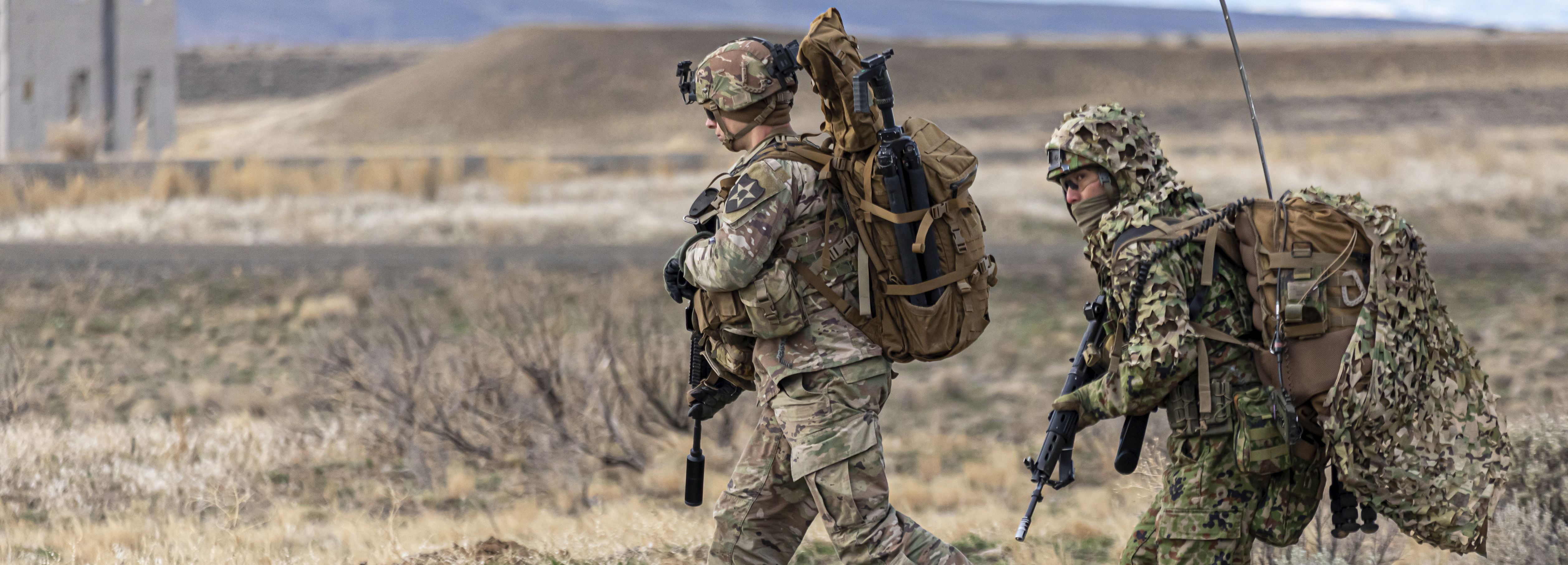 A soldier assigned to 2nd Stryker Brigade Combat Team, 7th Infantry Division alongside a member of the Japanese Ground Self-Defense Force run to a training objective during training exercise Rising Thunder on December 10, 2021 at Yakima Training Center, Wa.